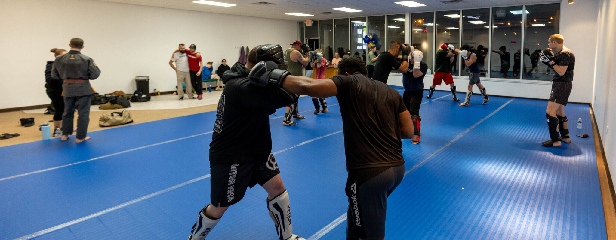 MMA students pair off in training while wearing full protective gear at Good Tree MMA gym in Wilkes Barre